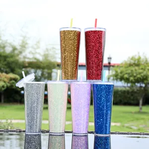 Gedetailleerd uitzicht op kleurrijke glitter plastic bekers met rietjes buiten.