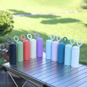 Outdoor detail shot of colorful stainless steel vacuum water bottles with ring lids on camping table.