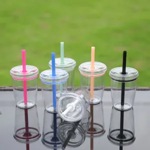 Details of clear plastic straw cup with colorful macaron lids and straws, outdoor setting.