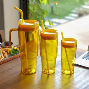 Detail shot of yellow plastic 40oz tumbler set with straws, cozy wooden table background.