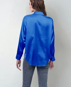 Back view detail of a vibrant royal blue satin long-sleeve blouse paired with grey pants.