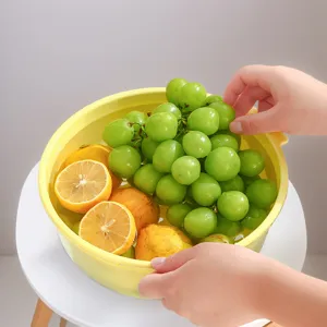 Detail view of washing fresh green grapes and lemons in a yellow plastic double layer draining basket.