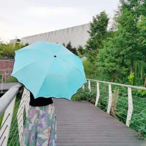 Vue détaillée de parapluie bleu clair pliable en trois avec volants en extérieur.