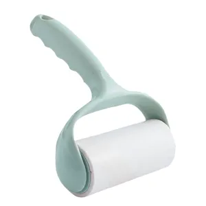Close-up of green handle sticky lint roller for clothes dust removal and pet hair cleaning.