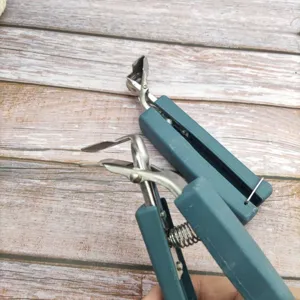 Close-up detail of the stainless steel anti-scald bowl clip with ergonomic blue handle.