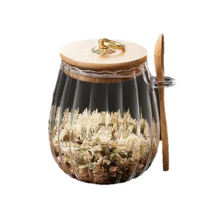 Clear glass storage jar with wooden lid and spoon, ribbed kitchen canister for sugar.