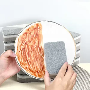 Close-up detail of double-sided cleaning sponge removing grease from dirty plate efficiently.