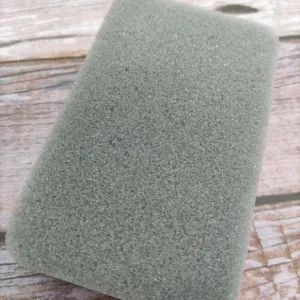 Gros plan d'une éponge de nettoyage grise, montrant sa texture poreuse et sa mousse durable.