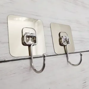 Close-up detail shot of two stainless steel adhesive wall hooks mounted on white wood texture.