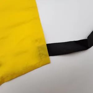 Vue de détail du tissu de tablier imperméable jaune et sangle noire attachée.