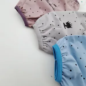 Detalle de mangas protectoras largas impermeables, diseño de lunares para limpieza de cocina.