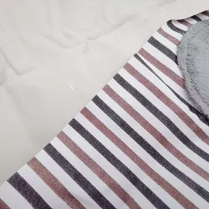 Gros plan du tissu de tablier rayé présentant un patch de texture en peluche grise douce.
