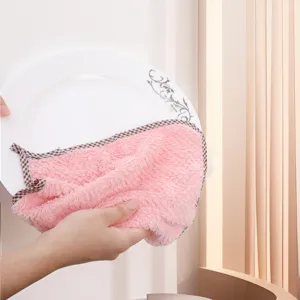 Detail view of the pink coral fleece dish towel wiping a plate, showing soft and absorbent texture.