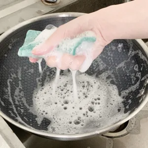 Vista dettagliata di spugna per pulizia bifacciale che produce schiuma lavando la padella.