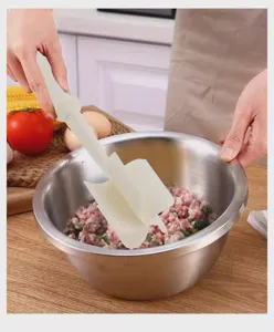 Handheld meat chopper detail showing plastic blade and stainless steel mixing bowl in kitchen.