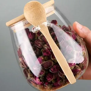 Glazen theebus met houten deksel en lepel, perfect voor het bewaren van thee en granen.