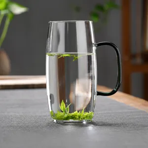 Borosilicaatglas thee mok detail, groene handgreep, hittebestendig, met verse theebladeren.