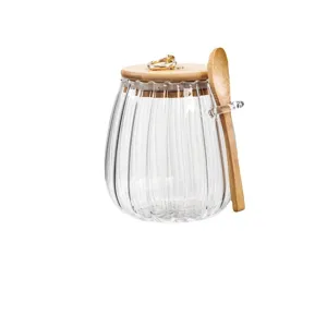 Glass tea storage canister with wooden lid and spoon, clear ribbed jar for kitchen organization.