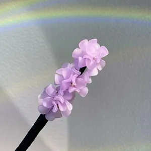 Nahaufnahme einer eleganten lila Hortensien Duttkissen Haarnadel, zartes florales Haaraccessoire.