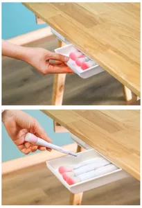 Close-up detail of white under desk sliding drawer installed on wooden table surface.
