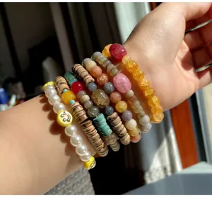 Detailansicht gestapelter bunter Edelsteinperlen-Armbänder mit süßen Smiley-Anhängern.