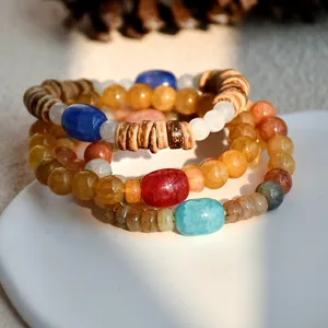 Detailaufnahme mehrlagiger, vintage-chinesischer bunter Kristall- und Holzperlen-Armbänder.