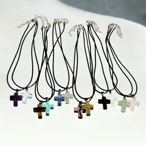 Close-up detail of colorful crystal cross pendants with black leather cord and metal clasp.