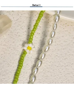 Gros plan détaillé d'un collier de perles vert menthe, mettant en valeur son joli pendentif floral.