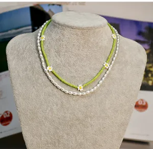 Vue détaillée du collier superposé de perles et de fleurs vert menthe, style tendance.