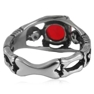 Anillo retro de acero inoxidable con hueso de calavera y piedra roja detalle cercano.