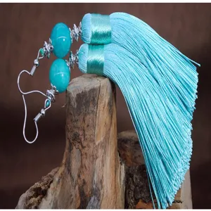 Primo piano di eleganti orecchini pendenti con nappe azzurre e perline, che mostrano dettagli.