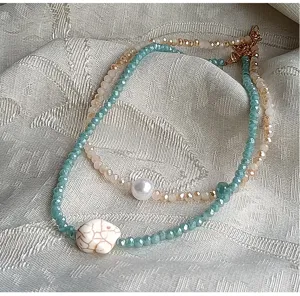 Primo piano di collana girocollo di cristallo a doppio filo con dettaglio di pietra.
