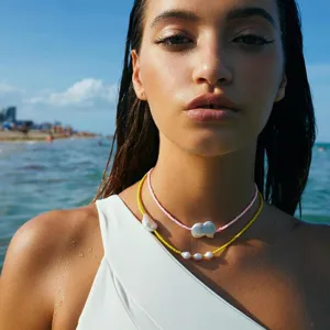 Dettaglio della collana girocollo con perline colorate e perle barocche in spiaggia.