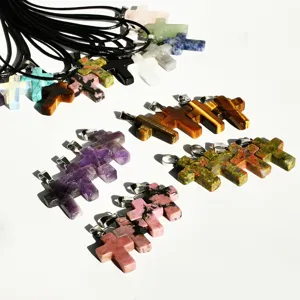 Close-up of assorted natural gemstone cross pendant necklaces with black leather cords, multi-color.
