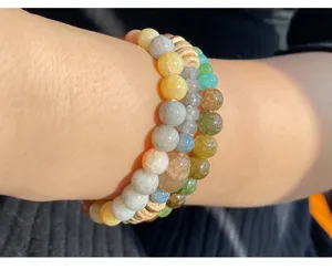 Schöne Detailaufnahme von bunten rissigen Achat Kristall Perlen Armbändern am Handgelenk.