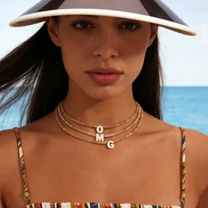 Primo piano di collana choker di perle di cristallo multistrato con ciondoli a lettera per l'estate.