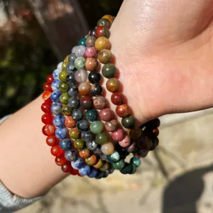 Nahaufnahme mehrstrangiger Naturstein-Perlenarmbänder gestapelt am Handgelenk, bunte 6mm Perlen.
