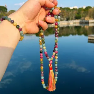 Gros plan de collier mala de perles de prière en tourmaline multicolore avec gland au soleil.