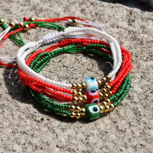 Pulsera artesanal multicapa de cuentas Miyuki con dijes de mal de ojo y cuerda trenzada.