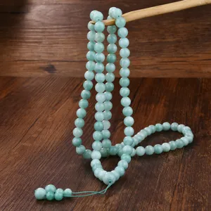 Dettaglio della lunga collana di perle in giada verde per preghiera in stile etnico.