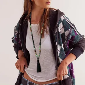 Detailopname van de lange boho kralenketting van natuursteen met een chique zwarte kwast hanger.