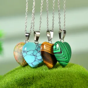 Primo piano di quattro collane con ciondolo in pietra a forma di cuore e catene argentate.