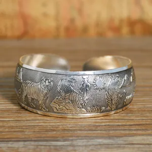 Primo piano del bracciale rigido vintage in argento con incisioni dettagliate di tigri.