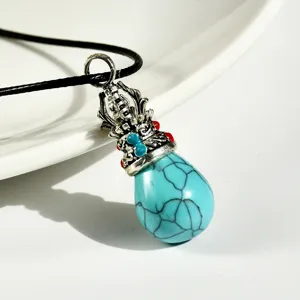 Close-up detail of vintage Tibetan turquoise teardrop crown pendant necklace with black cord.
