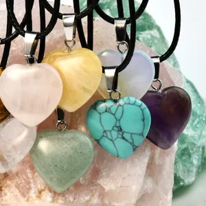 Close-up detail shot of colorful natural crystal heart pendants on black cord necklaces.