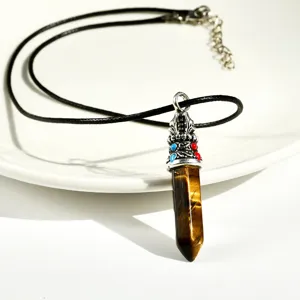 Detail shot of natural tiger eye stone hexagonal pendant with silver metal cap and black cord.