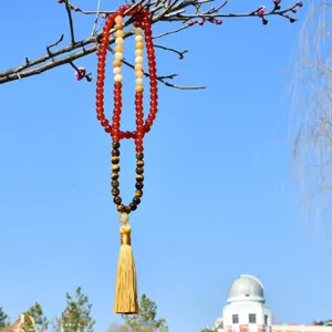 Primo piano ravvicinato e dettagliato della lunga collana con pietre colorate e nappa gialla.