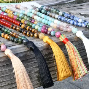 Collana lunga boho vintage con pietre naturali e nappina colorata da donna elegante.