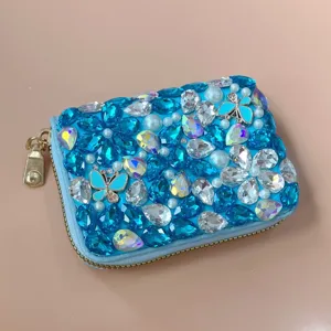 Close-up detail of a sparkling blue rhinestone wallet adorned with pearls and lovely butterflies.