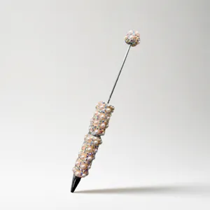 Beaded pen detail shot showing pearl and rhinestone decoration on metallic body for DIY crafts.